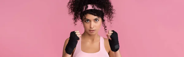 Encaracolado jovem mulher em sportswear com escravidão em mãos isoladas em rosa, banner — Fotografia de Stock