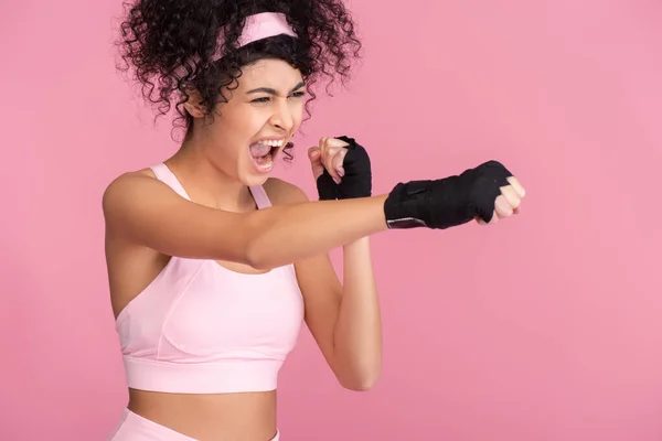 Encaracolado jovem mulher em sportswear com escravidão em mãos exercendo isolado em rosa — Fotografia de Stock