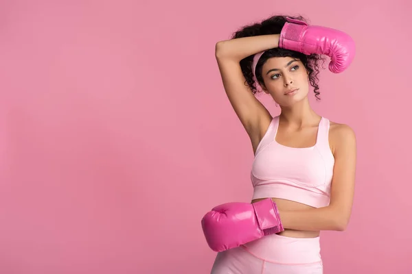 Morena e encaracolado mulher em sportswear e luvas de boxe isolado em rosa — Fotografia de Stock