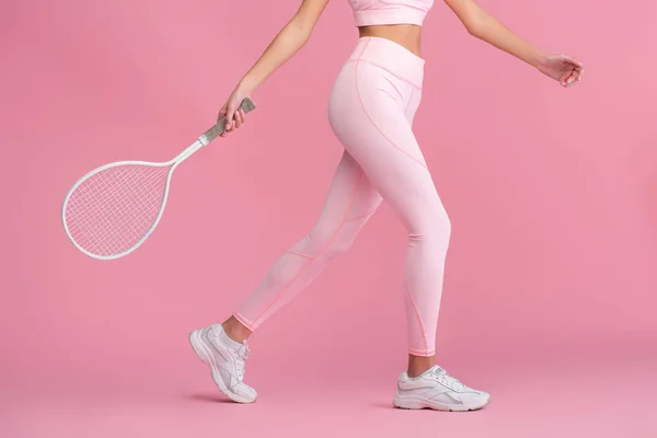 Abgeschnittene Ansicht einer jungen Frau in Sportkleidung mit Schläger beim Tennisspielen isoliert auf rosa — Stockfoto