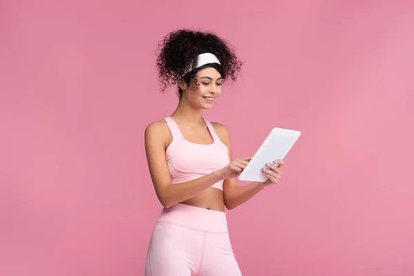 Веселая спортсменка с помощью цифрового планшета изолированы на розовый — стоковое фото