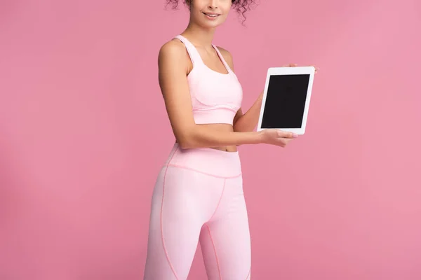 Cropped view of young sportswoman holding digital tablet with blank screen isolated on pink — Stock Photo