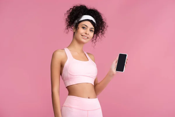 Deportista feliz celebración de teléfono inteligente con pantalla en blanco aislado en rosa - foto de stock