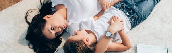 Vue aérienne de la mère avec des lèvres boudantes regardant sa fille allongée sur le sol, bannière — Photo de stock