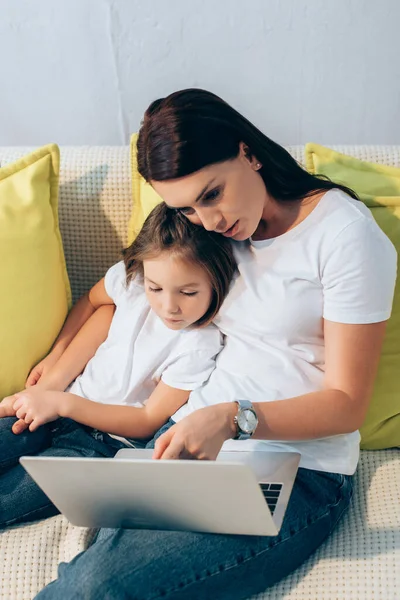 Mère et fille regardant ordinateur portable sur le canapé — Photo de stock