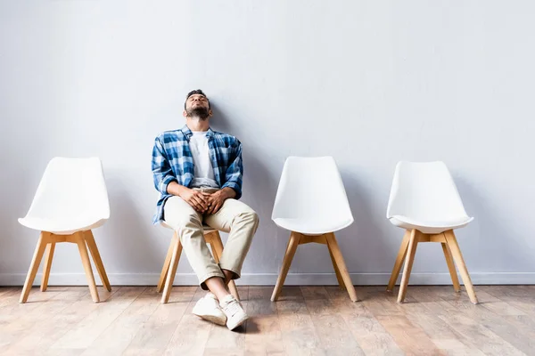 Tired man sitting on chair while waiting in hall — Stock Photo