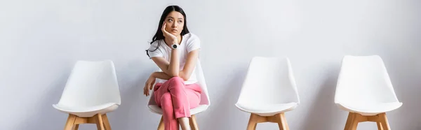 Donna asiatica seduta con gambe incrociate vicino a sedie in sala, striscione — Foto stock