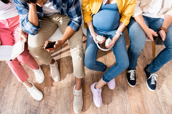 Top view of man using smartphone near pregnant woman and people in queue — Stock Photo