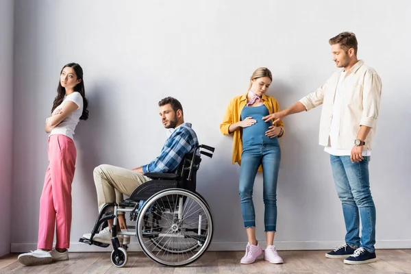 Multicultural people, pregnant woman and disabled man in wheelchair waiting in hall — Stock Photo