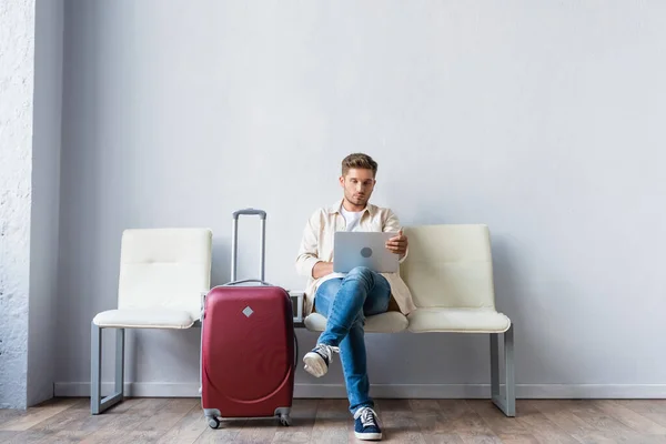 Чоловік використовує смартфон біля валізи в аеропорту — стокове фото