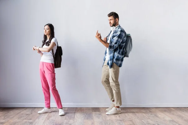 Student showing middle finger near asian woman in hall — Stock Photo