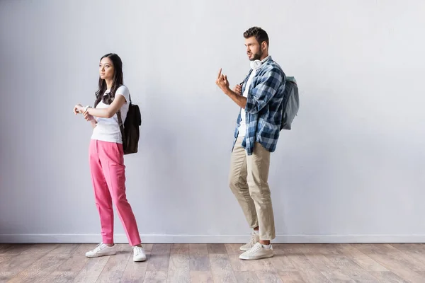 Estudiante mostrando medio dedo cerca asiático mujer en hall - foto de stock