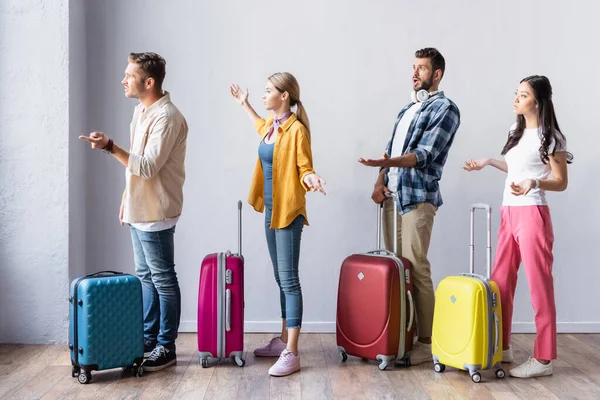 Angry multiethnic people with suitcases pointing with hands in hall of airport — Stock Photo