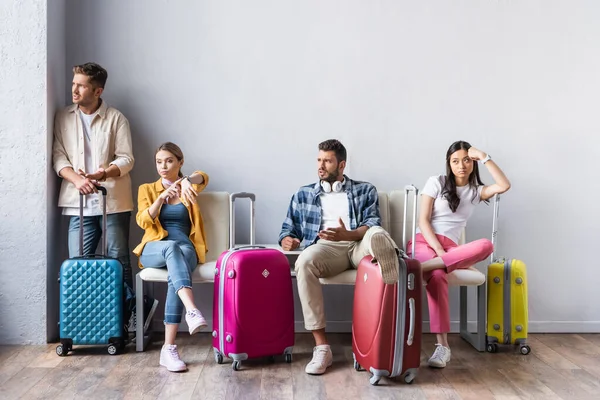 Gestresste multikulturelle Menschen, die in der Nähe von Koffern in der Flughafenhalle wegschauen — Stockfoto