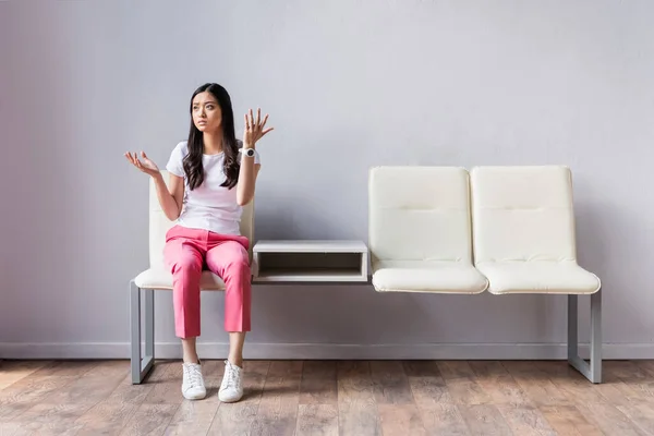 Insoddisfatto asiatico donna guardando lontano mentre in attesa in sala — Foto stock