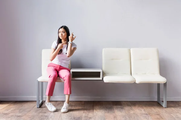 Femme asiatique pointant du doigt à la montre-bracelet sur les chaises — Photo de stock