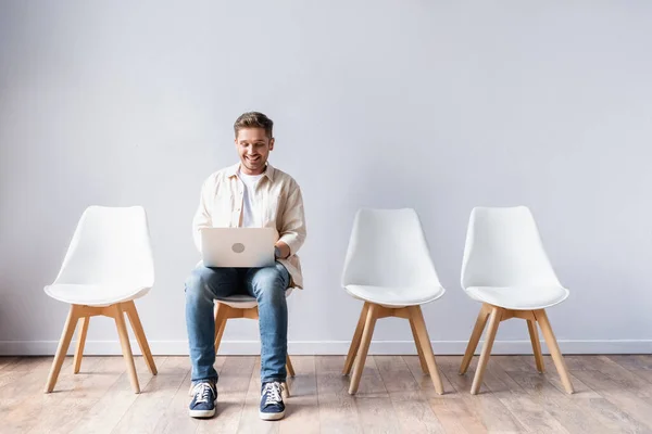 Freelance sorridente che usa il computer portatile mentre aspetta in sala — Foto stock