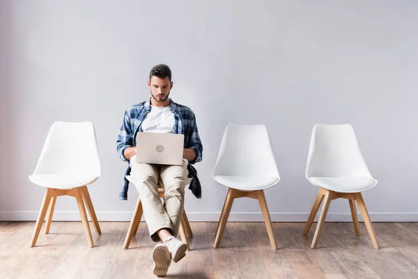 Freelancer in casual clothes using laptop in hall — Stock Photo