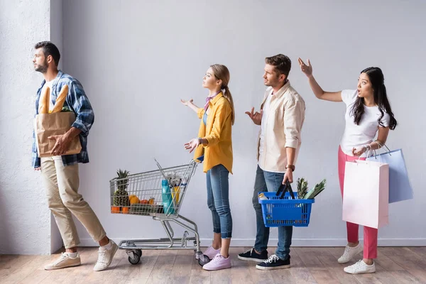 Clienti multiculturali arrabbiati con acquisti che puntano con le mani in coda — Foto stock