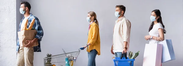 Pessoas multiculturais em máscaras médicas segurando sacos de compras e compras na loja, banner — Fotografia de Stock