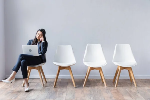 Asiática mujer de negocios utilizando portátil en sala mientras espera entrevista de trabajo - foto de stock
