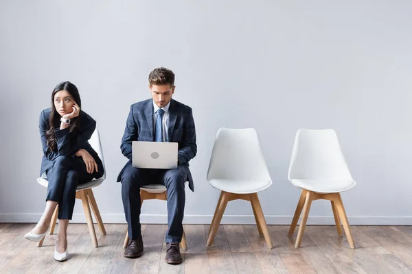 Asiatique femme d'affaires assis près de l'homme d'affaires avec ordinateur portable en attendant entrevue d'emploi — Photo de stock