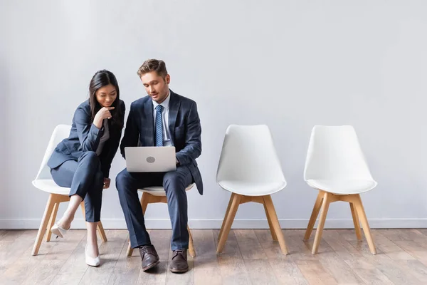 Sorrindo asiático empresária sentado perto de empresário com laptop antes de entrevista de emprego — Fotografia de Stock