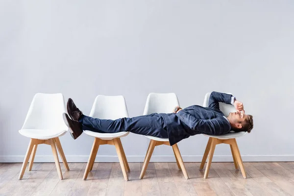 Uomo d'affari in giacca e cravatta sdraiato sulle sedie in attesa di colloquio di lavoro — Foto stock