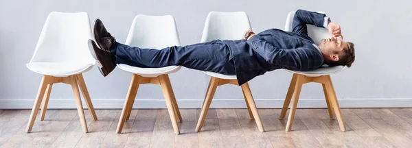 Businessman in formal wear lying on chairs in hall, banner — Stock Photo