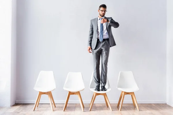 Uomo d'affari in giacca e cravatta guardando orologio da polso in attesa in sala — Foto stock