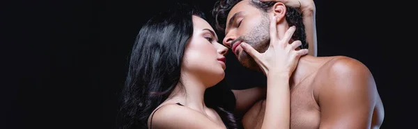 Sexy brunette femme embrassant cou de jeune homme isolé sur noir, bannière — Photo de stock