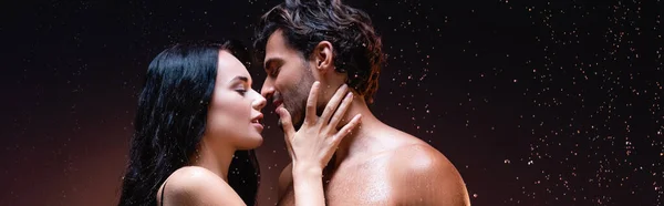 Seitenansicht der sexy Frau in der Nähe junger Mann ohne Hemd unter Regen auf dunklem Hintergrund, Banner — Stockfoto