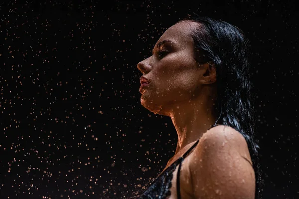 Чуттєва, мокра жінка позує під дощем на темному фоні — стокове фото