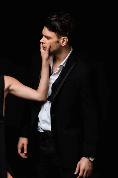 Woman touching face of man in suit isolated on black — Stock Photo