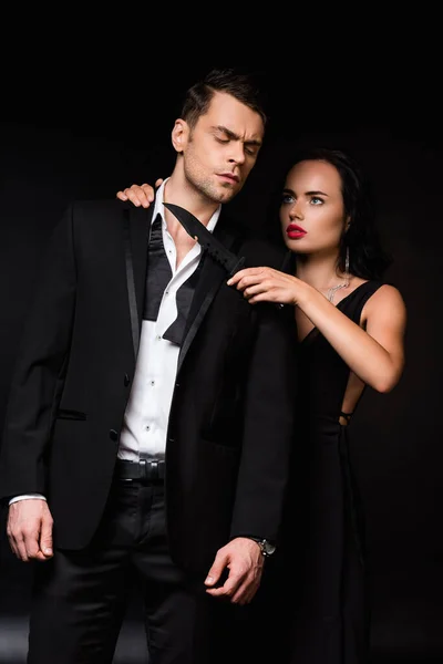 Gefährliche Frau hält Messer am Hals von Mann im Anzug isoliert auf schwarz — Stockfoto