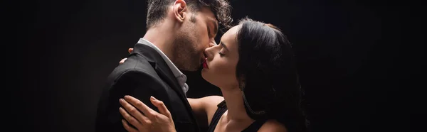 Сексуальна жінка з червоними губами цілується з чоловіком у костюмі ізольована на чорному, банер — стокове фото