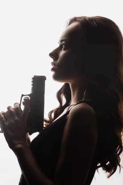 Seitenansicht der lockigen brünetten Frau mit Pistole isoliert auf weiß — Stockfoto