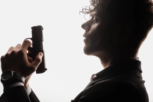 Side view of armed man in formal wear holding gun isolated on white — Stock Photo