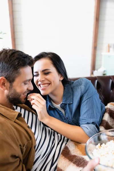 Excited woman with closed eyes feeding boyfriend with popcorn, blurred foreground — Stock Photo