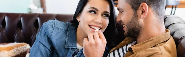 Молодой человек кормит веселую девушку попкорном, плакатом — Stock Photo