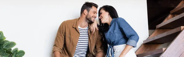 Glückliches junges Paar in stylischer Freizeitkleidung, das sich auf Holztreppen anschaut, Banner — Stockfoto