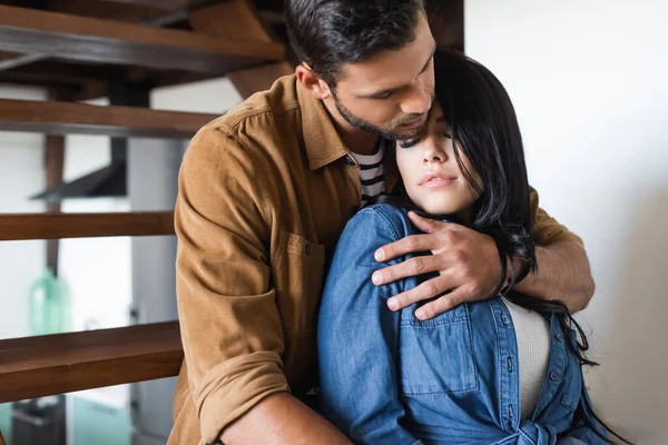 Giovane uomo abbracciando ragazza bruna su scale di legno a casa — Foto stock