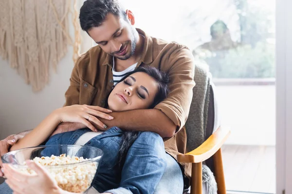 Felice uomo abbracciare fidanzata tenendo ciotola di popcorn con gli occhi chiusi — Foto stock