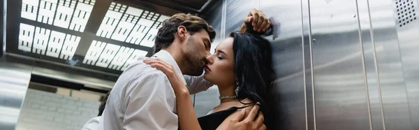 Young man kissing sensual elegant woman in elevator, banner — Stock Photo