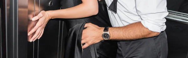 Partial view of man embracing woman in black dress in elevator, banner — Stock Photo