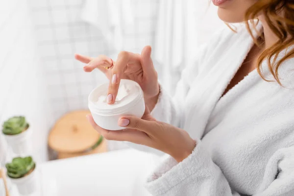 Vista recortada de la mujer sosteniendo crema cosmética en el baño — Stock Photo