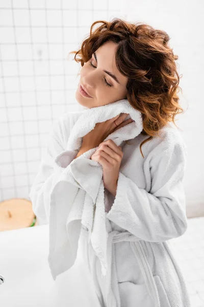 Mujer en albornoz secado cuello con toalla en el baño — Stock Photo