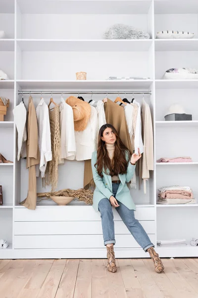 Pensive woman touching shirt in wardrobe at home — Stock Photo