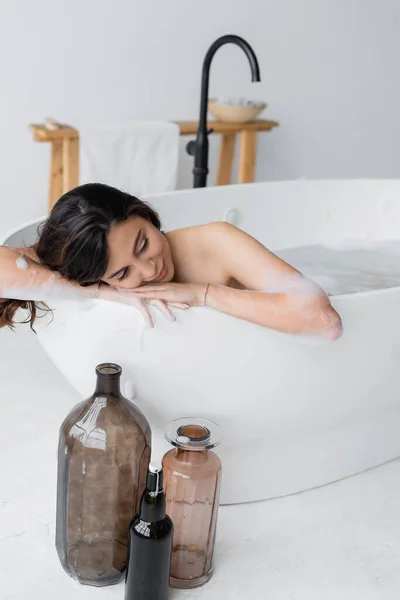 Mujer joven en espuma relajante mientras toma baño en baño moderno - foto de stock