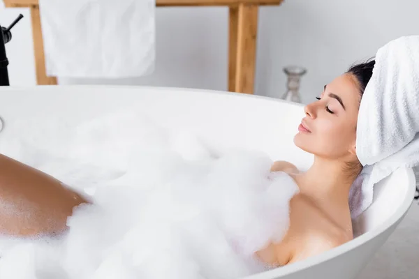 Mujer joven en toalla en la cabeza tomando baño - foto de stock